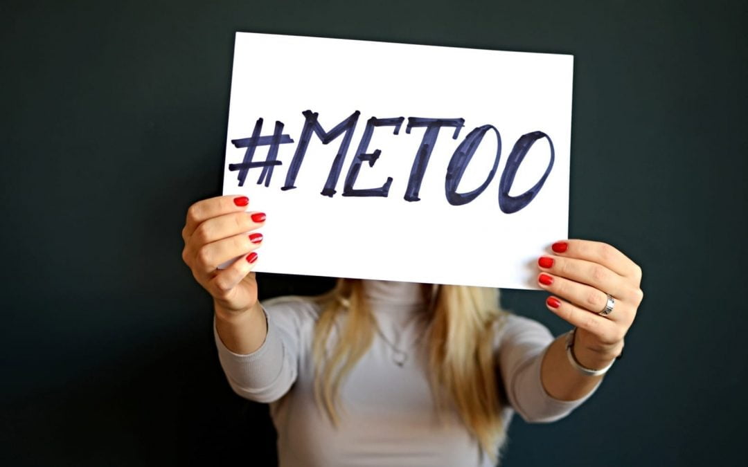 A woman holding a sign with #metoo written in black marker