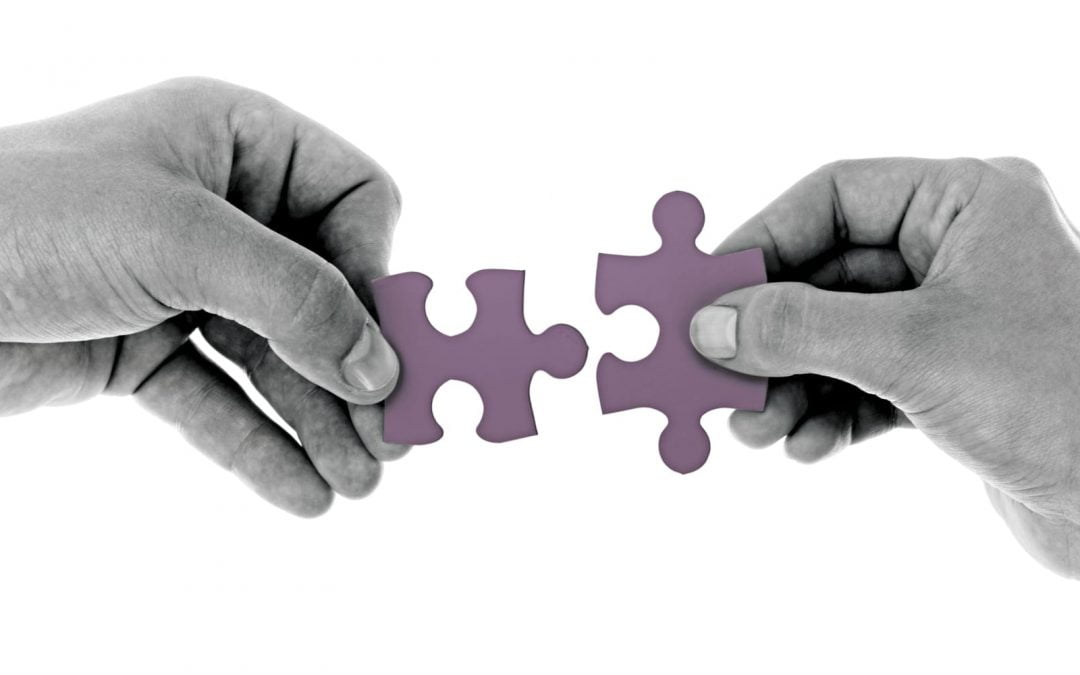 Hands holding puzzle pieces together