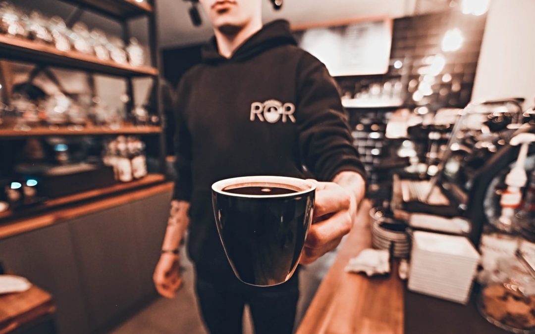 A barista holding out a cup of coffee