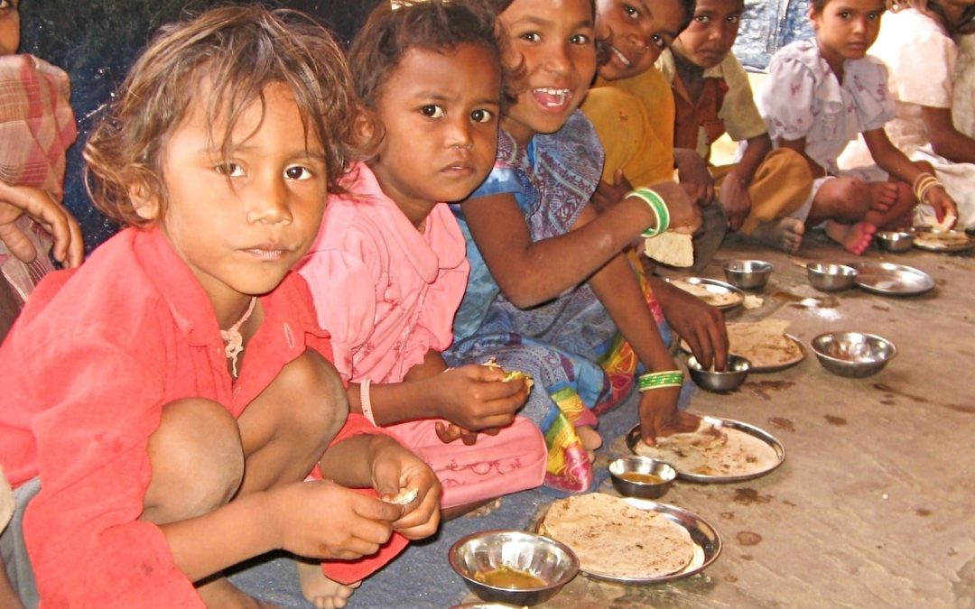 Children squatting in front of plates of food