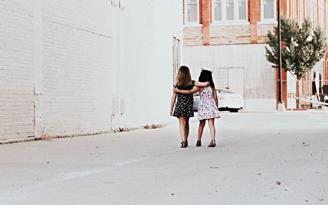 Two girls walking arm in arm