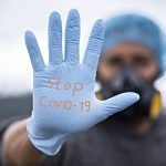 Medical person wearing glove with Stop COVID-19 on it