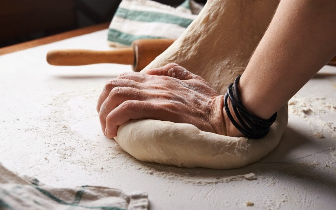 A person kneading dough on a kitchen counter.