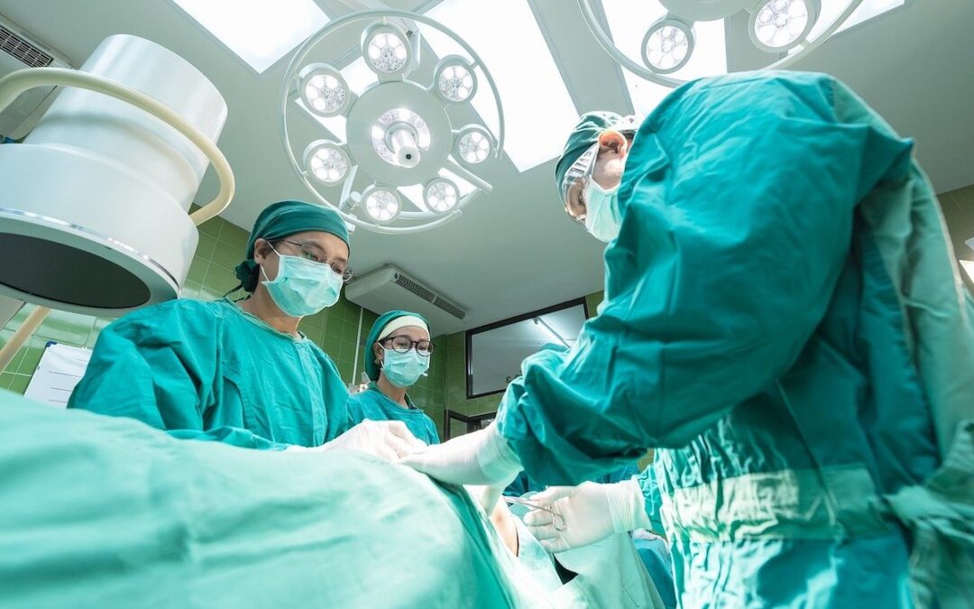 Doctors in green scrubs operating on a patient.