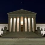 The exterior of the Supreme Court of the U.S. building at night.