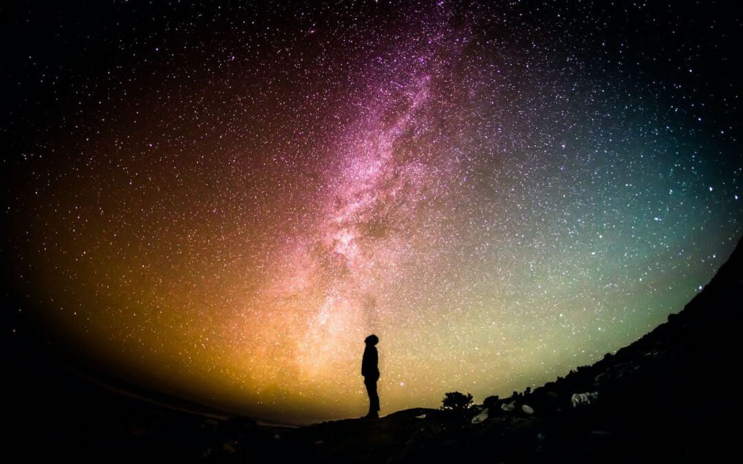 A person standing outside at night staring up at the stars.