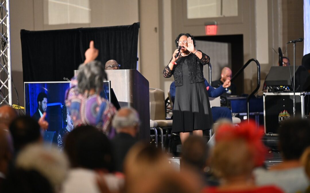 A woman standing on a stage preaching.