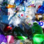 A closeup of a large pile of used, empty plastic bottles and aluminum soda cans.