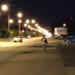A person, slightly blurry in the distance, walking down a street at night.