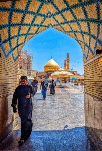 People walking outside with a mosque in the background in Samarra, Iraq.