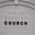 A white brick wall with the word “church” on it in black letters, with missing letters above it.