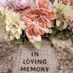 A bouquet of flowers on a gravestone inscribed with the statement, “In Loving Memory.”