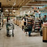 The interior a grocery store with several shoppers waiting in line to check out.