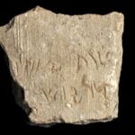 An inscription on a pottery shard set against a black background.