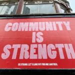 A red sign with white letters that says, “Community is Strength.”