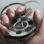 A hand holding an 8mm film movie.