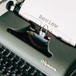 A black typewriter with the word review typed and centered.