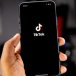 A person holding a phone opened to the TikTok app.