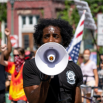 A photo of an organizer speaking into a bullhorn at a protest