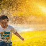 A young child playing in a water sprinkler.