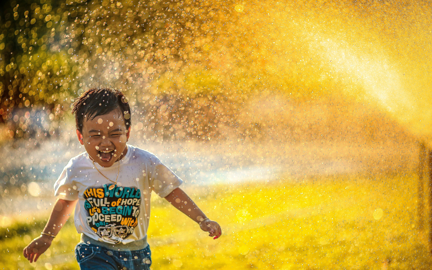 A young child playing in a water sprinkler.