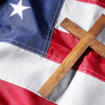 A cross laying on an American flag.