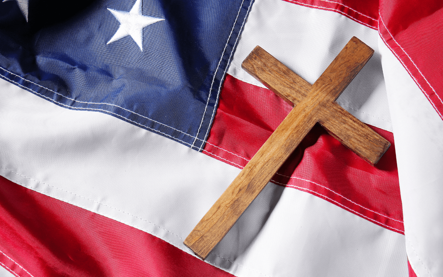 A cross laying on an American flag.