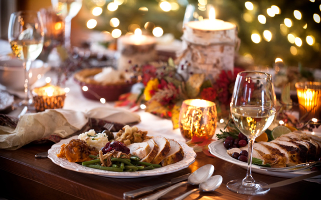 A table with plated sliced turkey, green beans, mashed potatoes, sweet potatoes, and cranberry sauce.