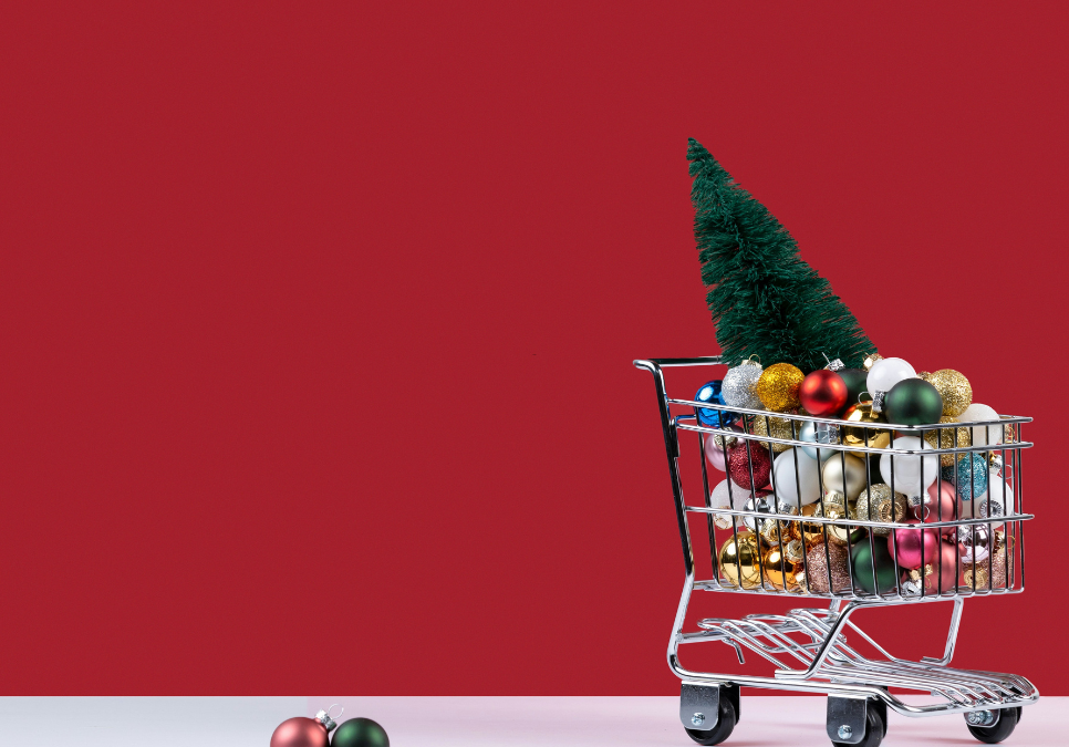 An image of a shopping cart filled with Christmas decorations and two Christmas ornaments on the ground.