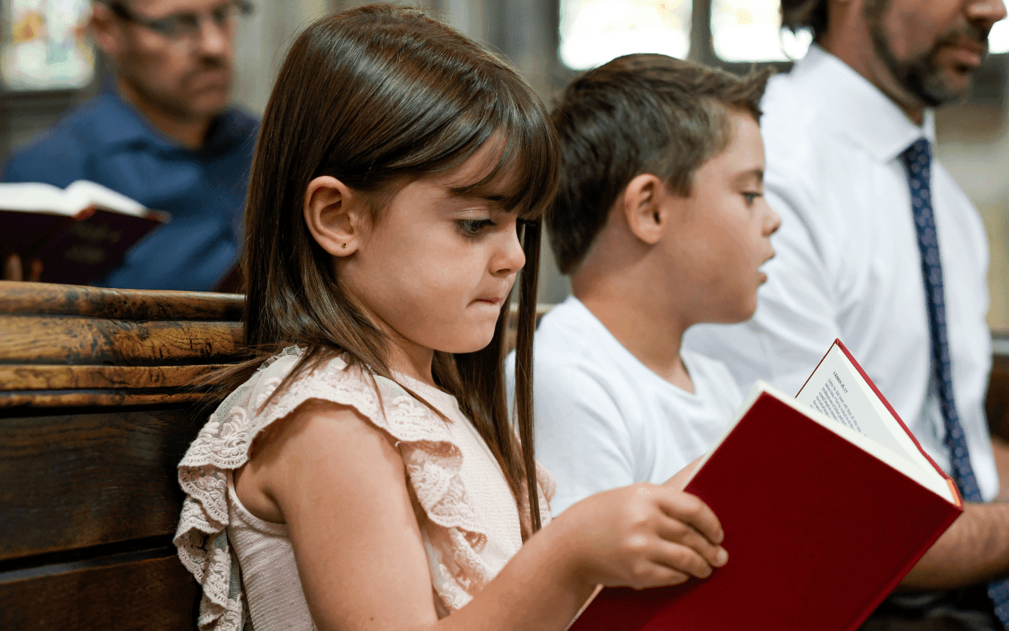 A young girl and boy are sitting in a pew during worship.