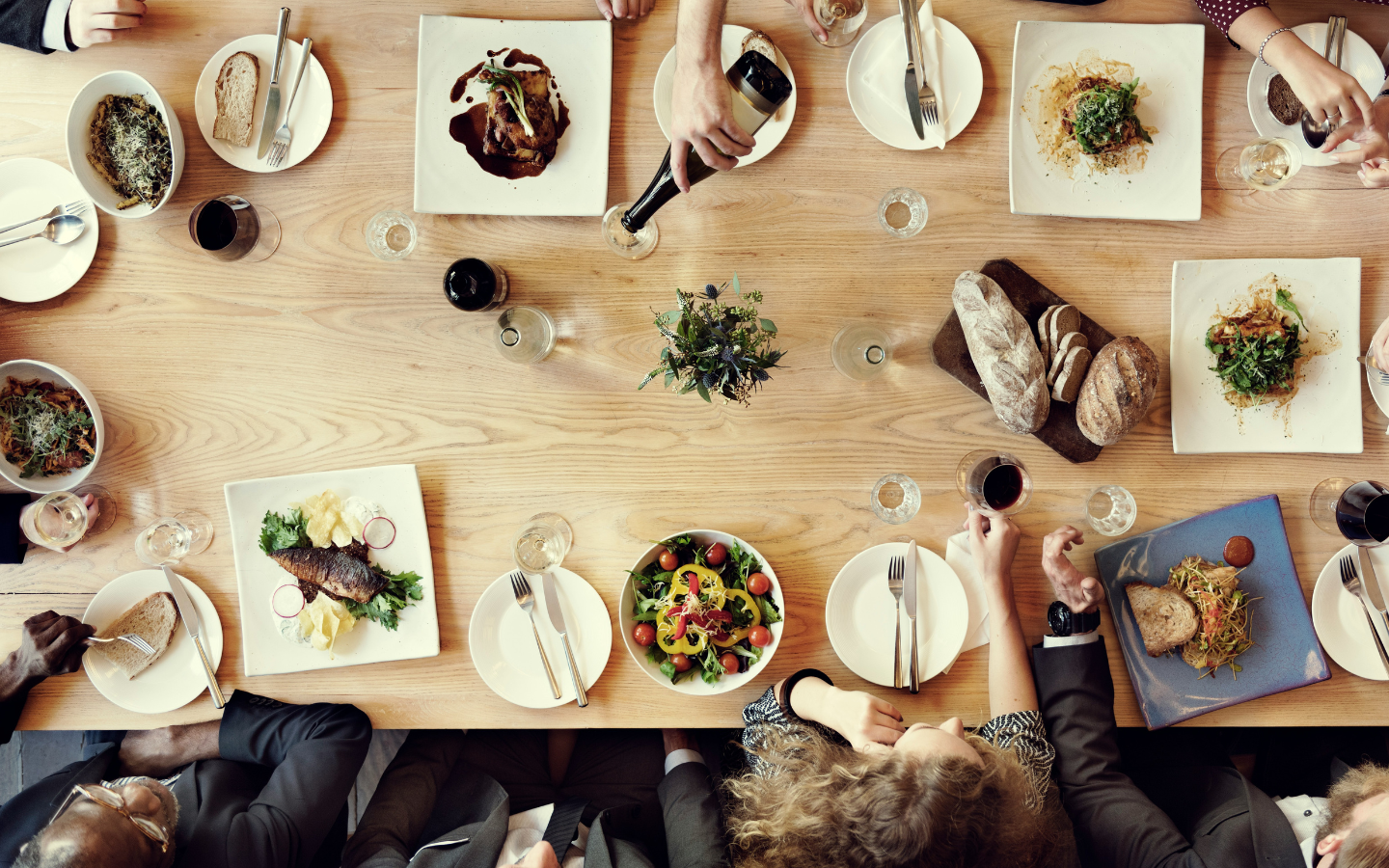 A photo of people eating at a dinner table taken from an aerial view.