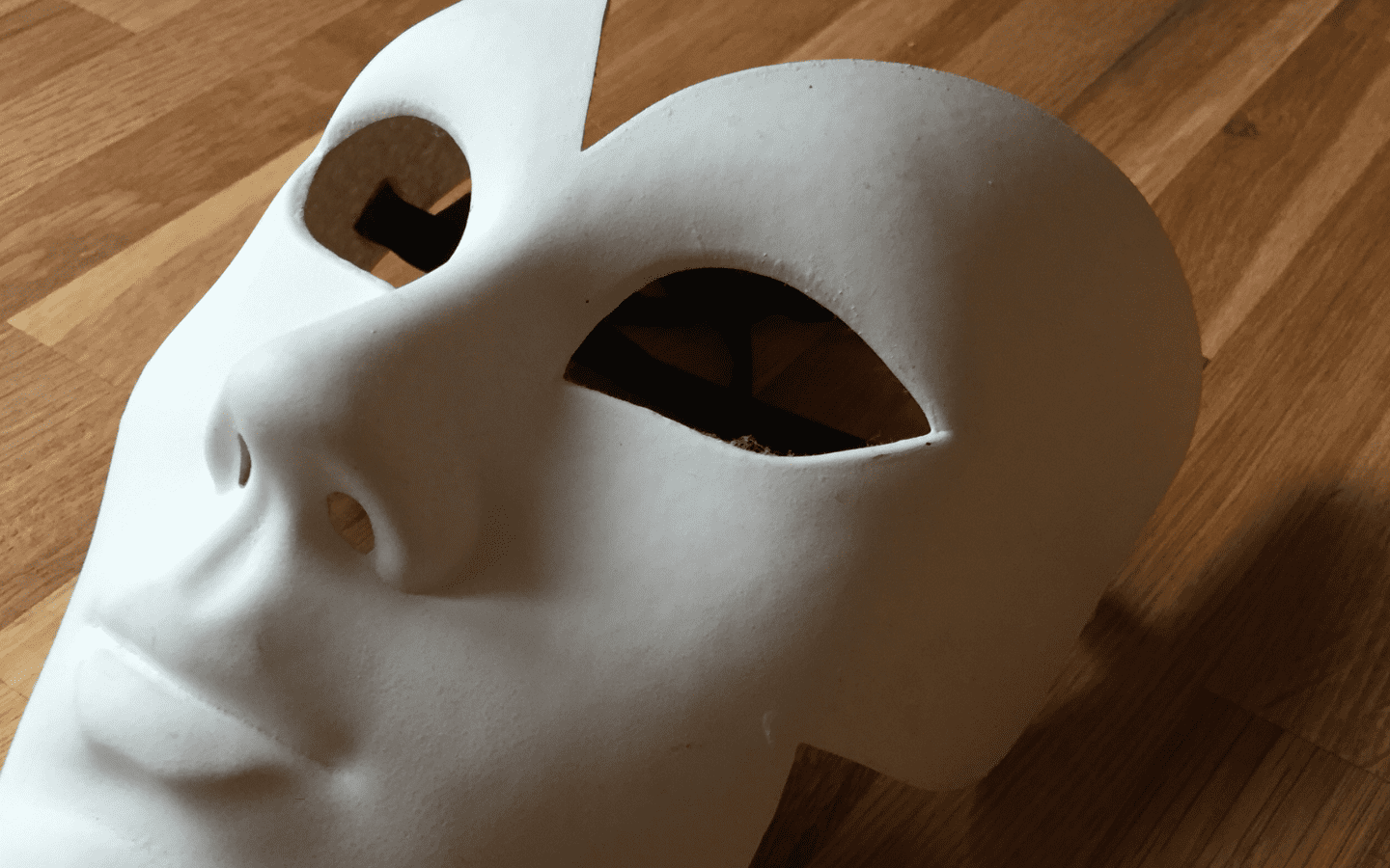 A photo of a plain white mask lying on a flat surface.