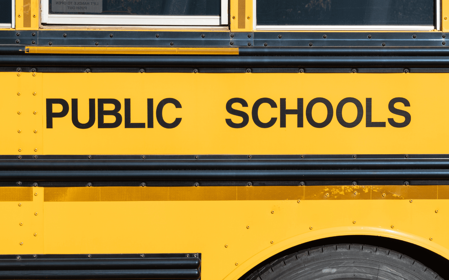 The photo of a side of a school bus with the words “Public Schools.”