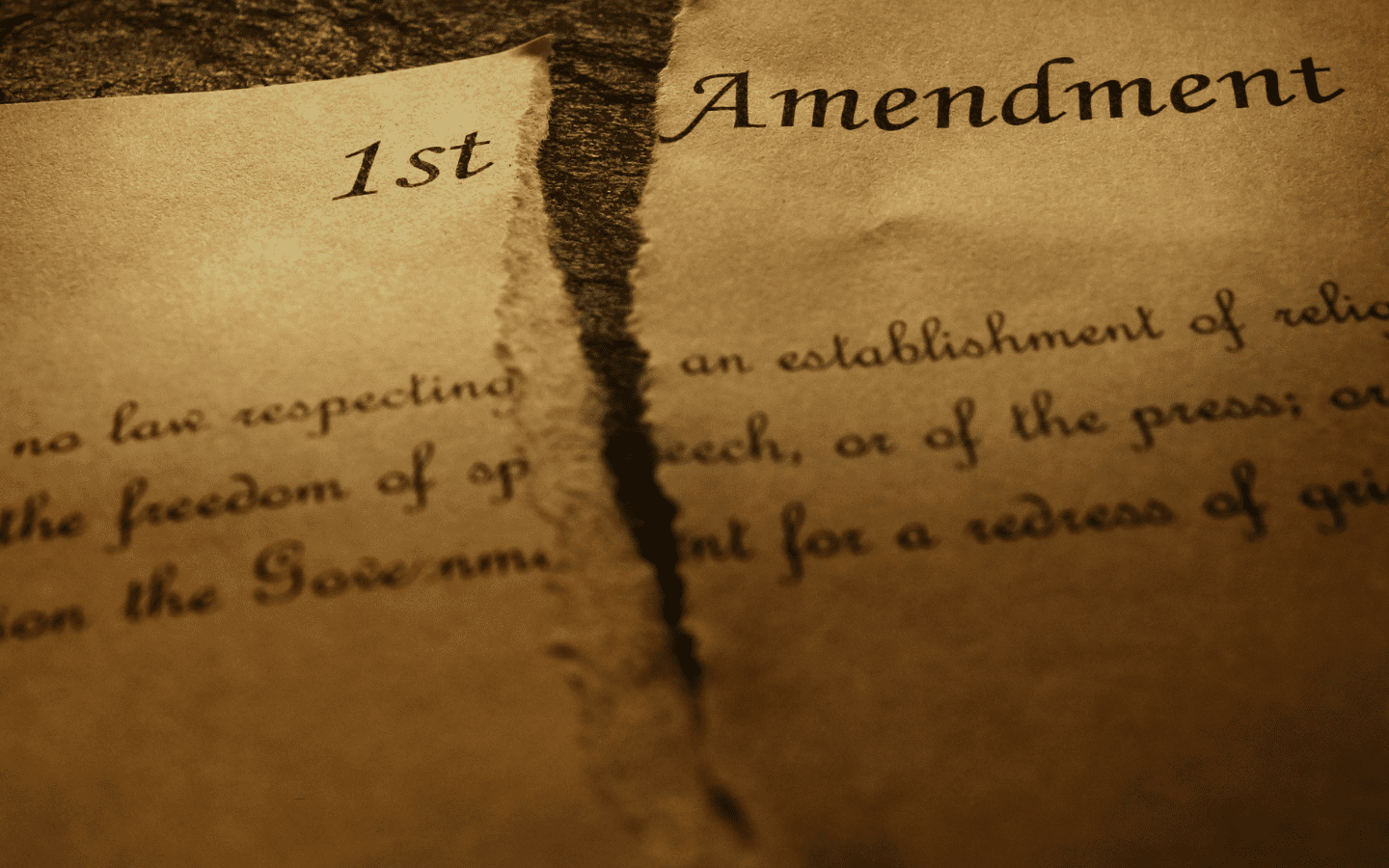 A representation of the first Amendment of the U.S. Constitution being torn in half.