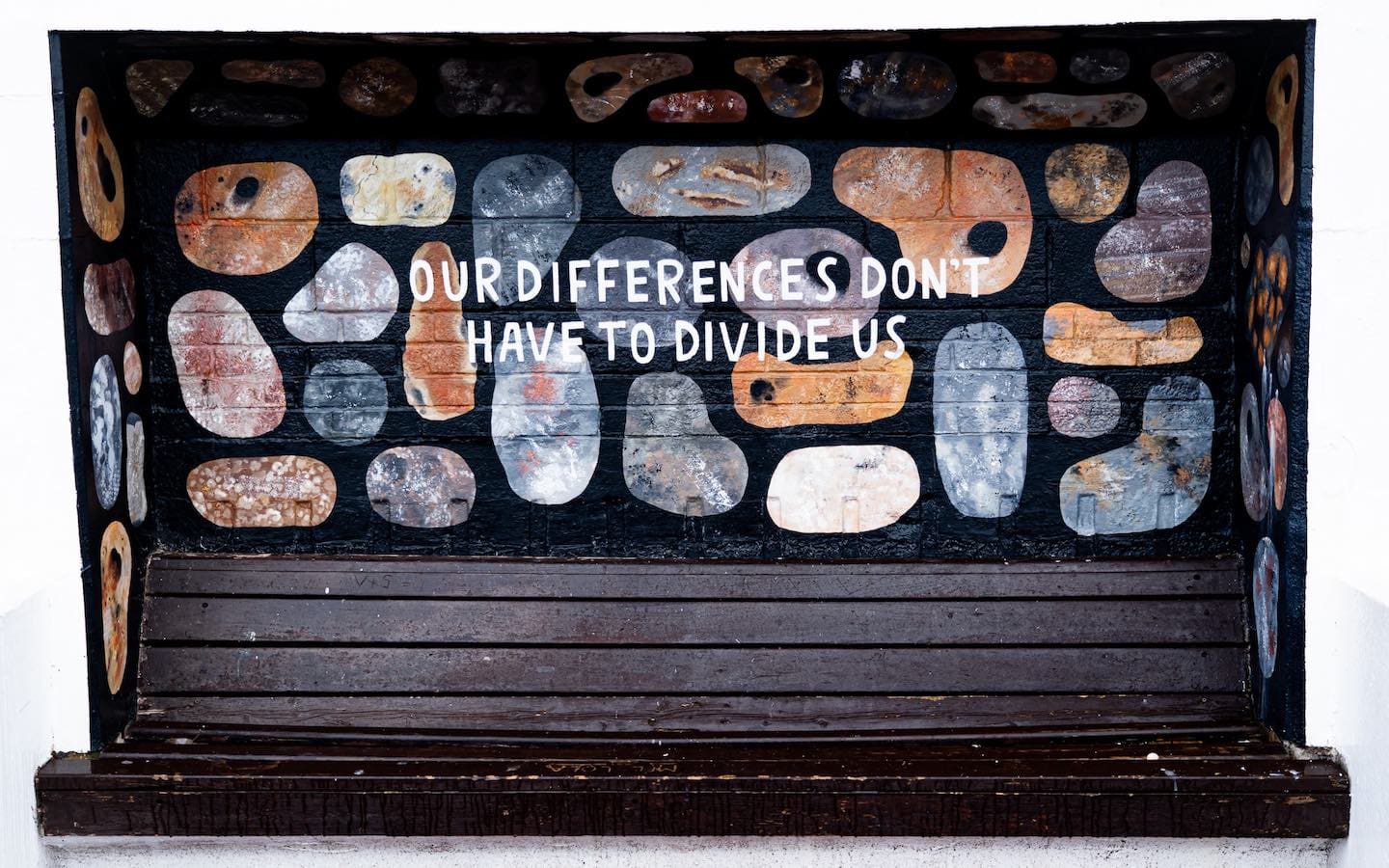 A mural on a cinder-block wall featuring rocks of various sizes with the words