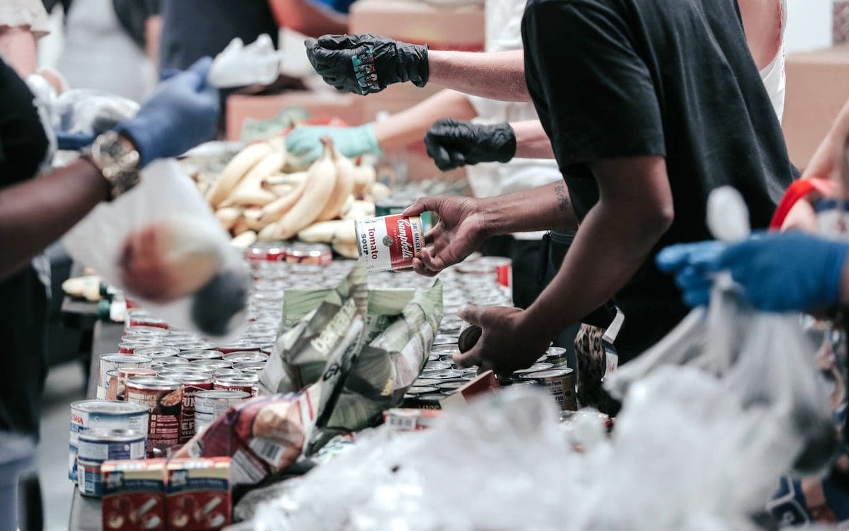 A table filled with food and volunteers handing out items.