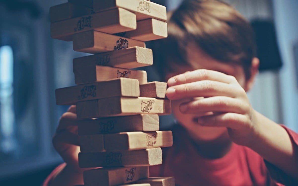 A young boy playing with stack of Jenga blocks.
