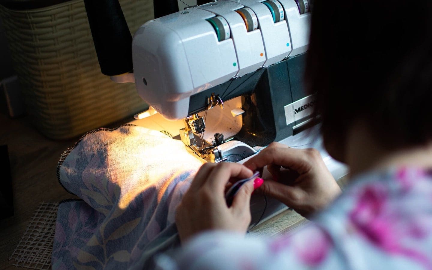 A person sewing a garment with a sewing machine.