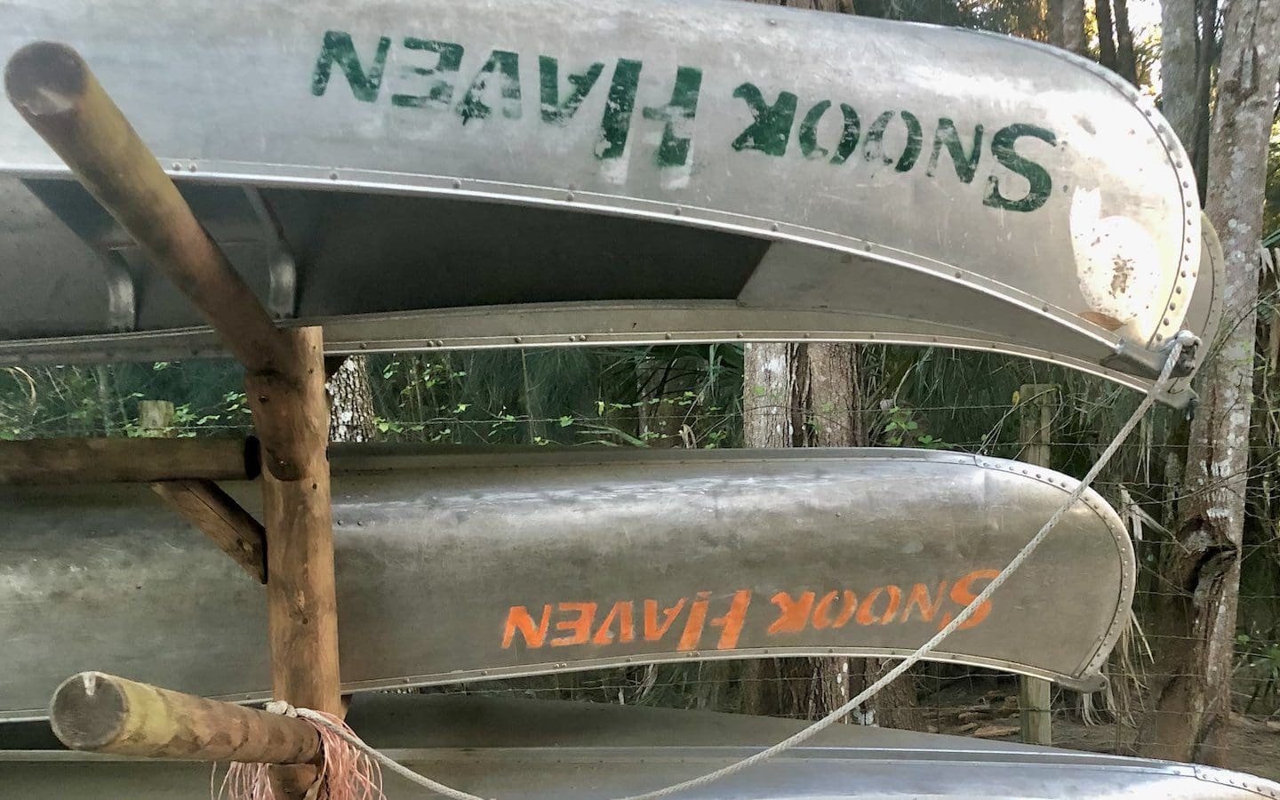 Several aluminum canoes sitting upside down on a storage rack.
