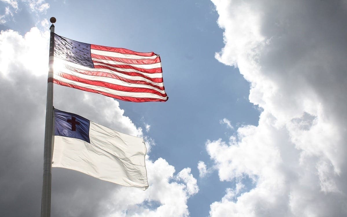 A flag pole with a U.S. flag flying above a Christian flag.