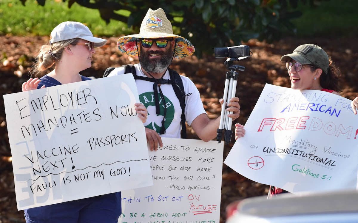 Protestors holding signs at a protest opposing COVID-19 vaccine mandates.
