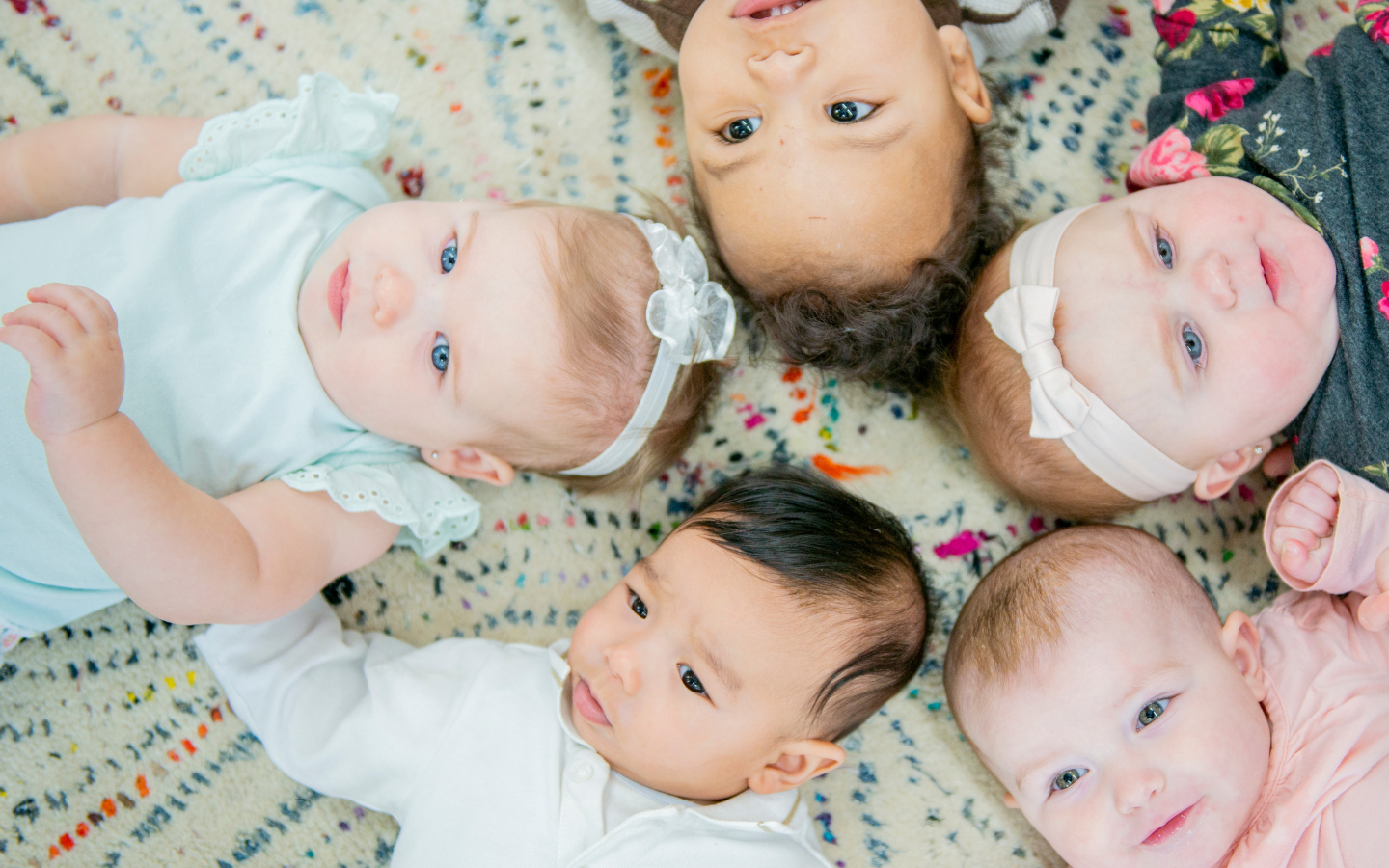 A group of babies laying on their backs in a circle.