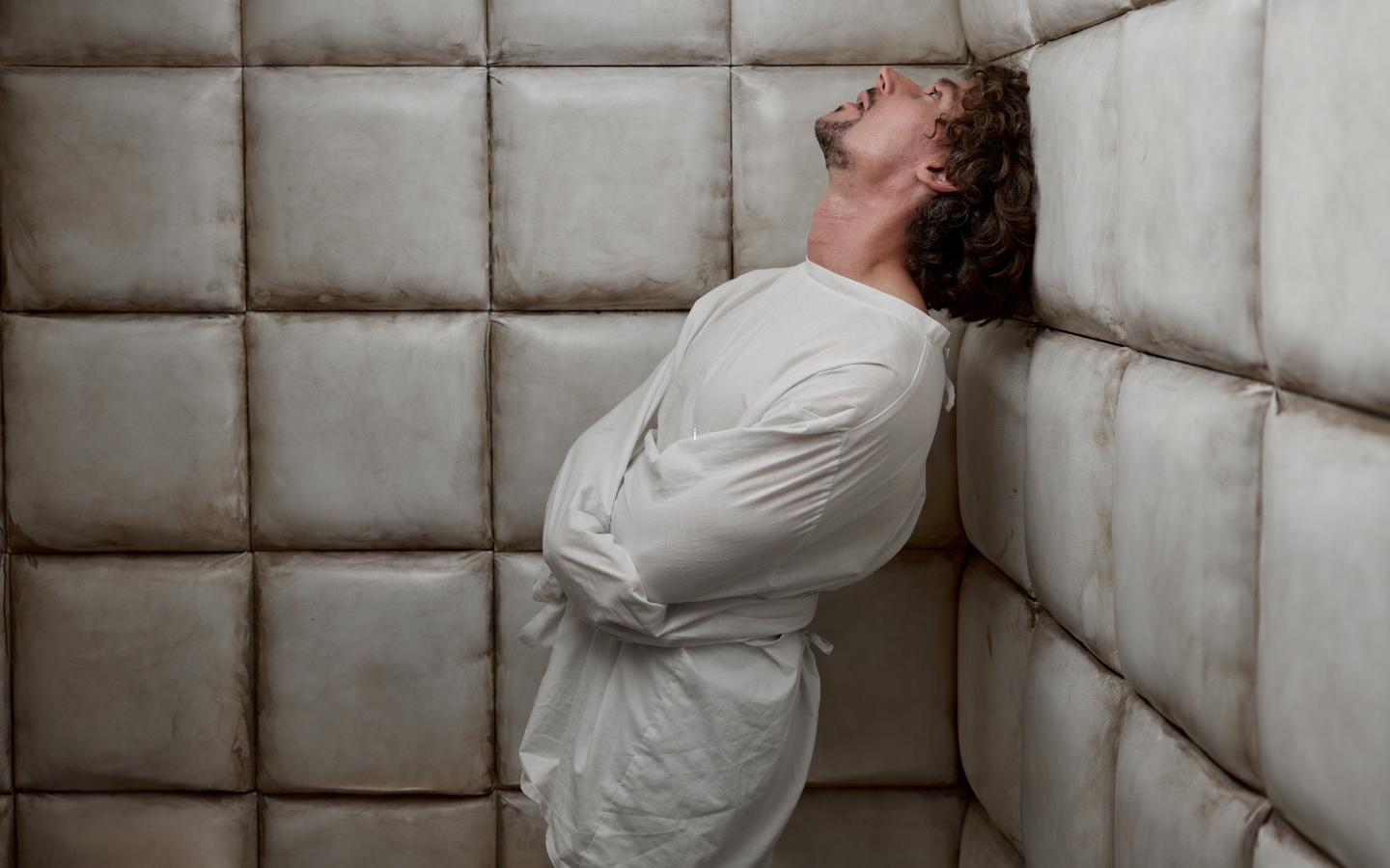 A man in a straight-jacket in a padded room.