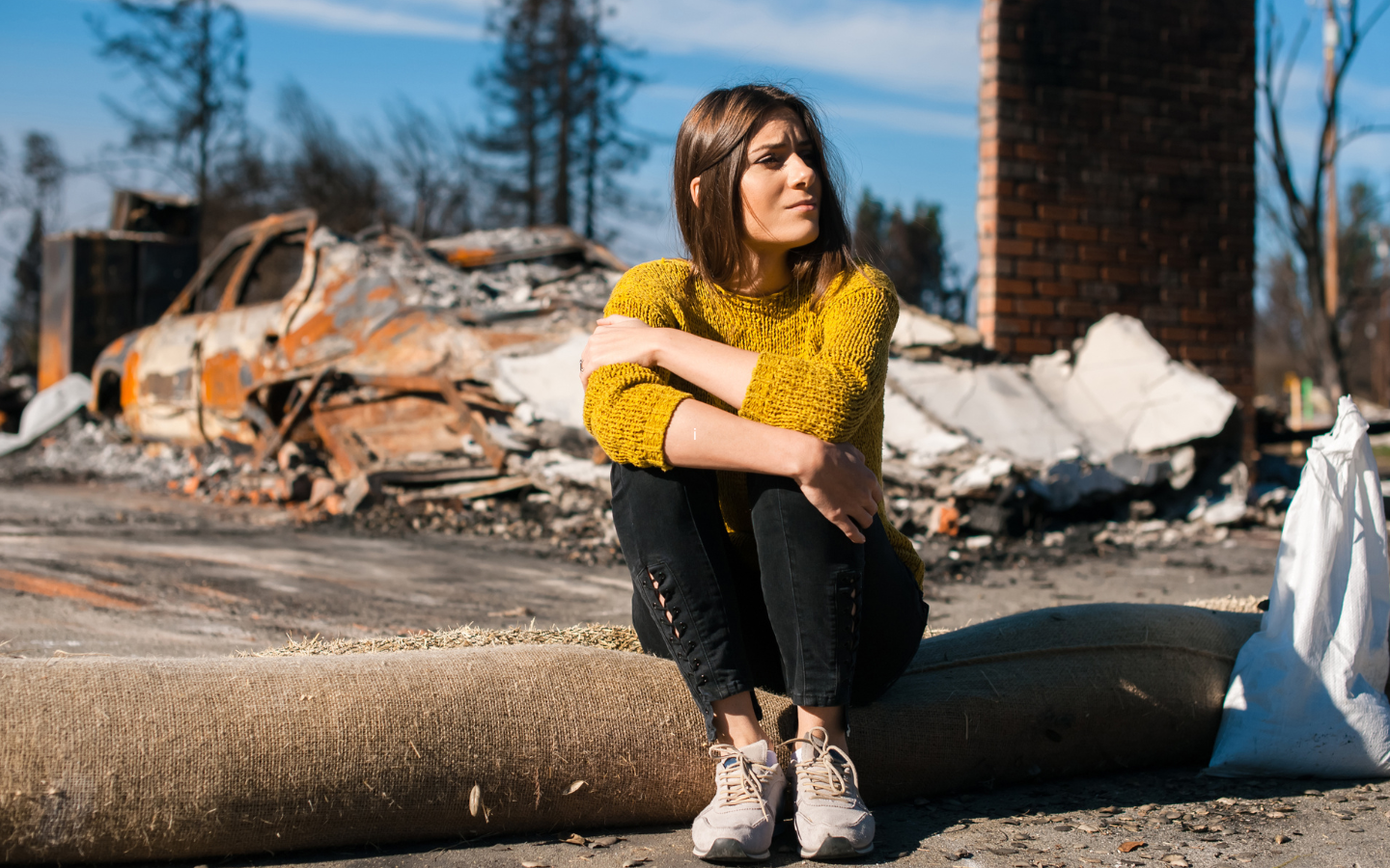 A woman sits outside a house destroyed by fire, wondering what to do next.