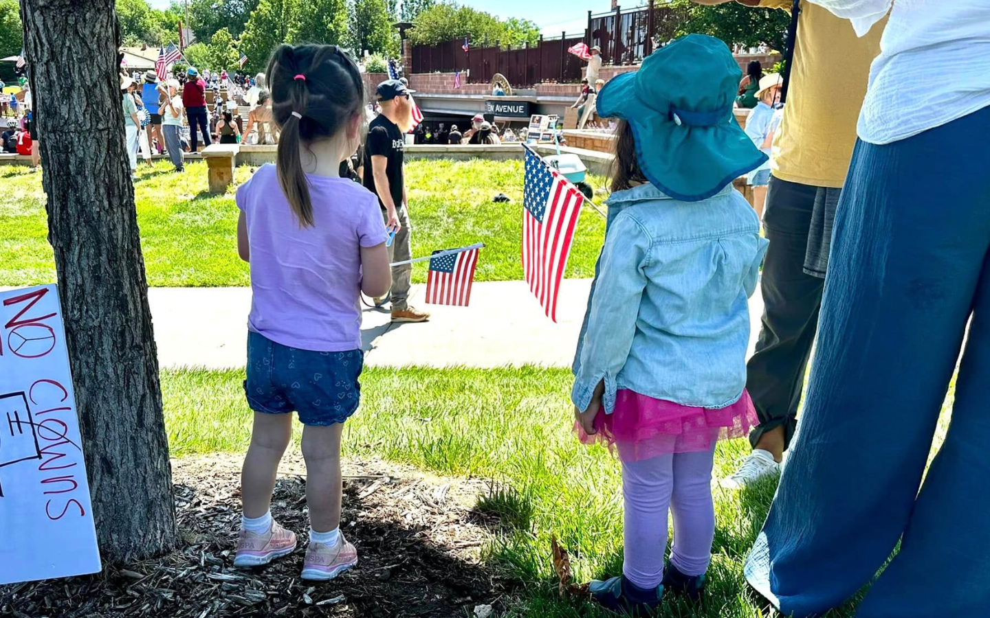 A photo of two young girls holding American flags at the No Kings Rally in Arvada, Colorado.